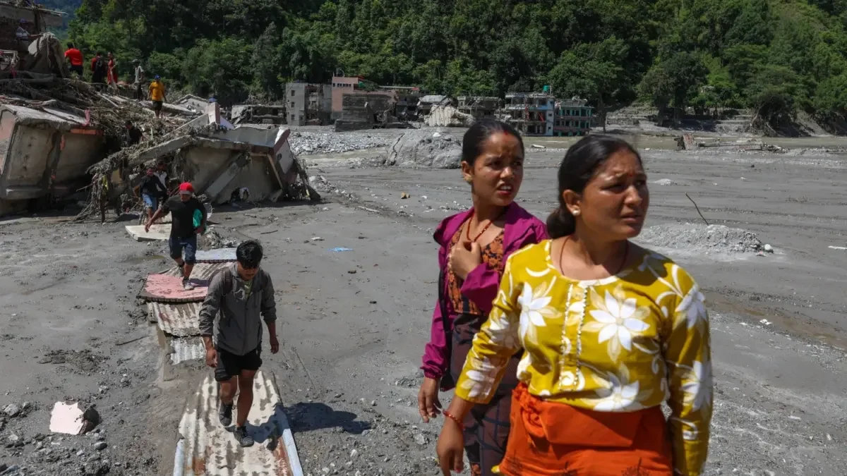 Two women in the foreground and others survey the mud, after the flood. Photo by Suman Nepali of Nepali Times. Used with permission.